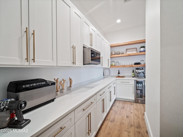2540 W Oasis Springs Ct, Tucson, AZ 85742 - kitchen with open shelves, white cabinets, stainless steel microwave, beverage cooler, and light wood-style flooring