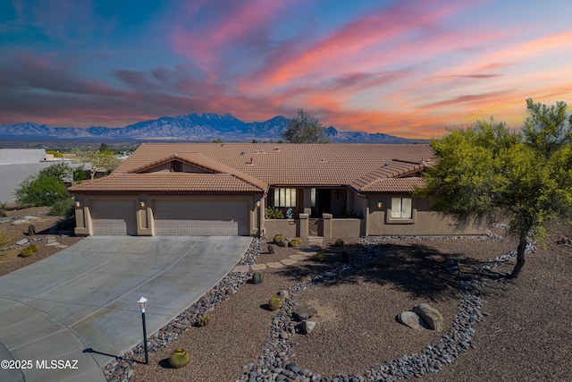ranch-style home featuring an attached garage, concrete driveway, stucco siding, and a tiled roof