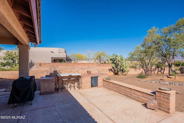 view of patio featuring outdoor dry bar, a fenced backyard, and grilling area