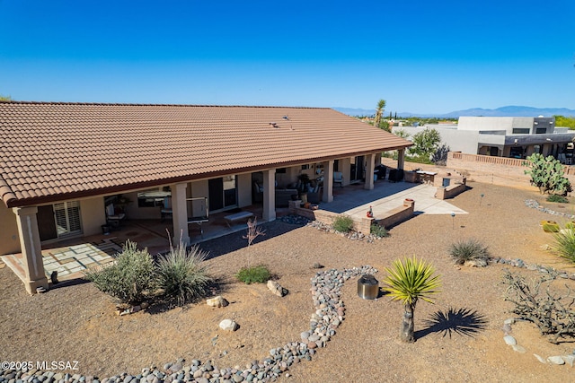 back of property featuring a patio, a mountain view, and a tiled roof