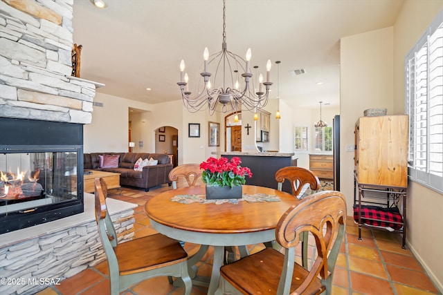 dining space featuring arched walkways, a chandelier, visible vents, and a fireplace