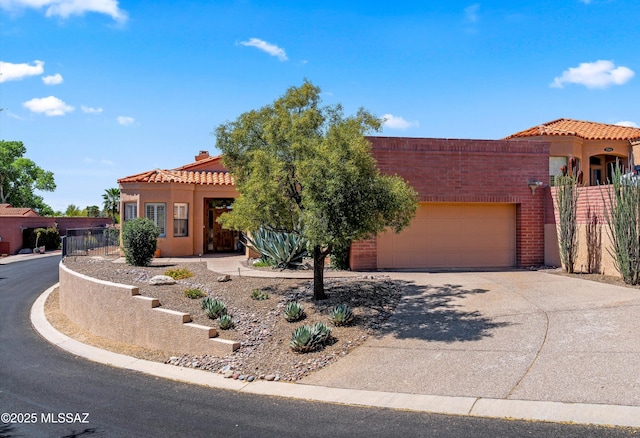 view of front of house featuring an attached garage, a tile roof, stucco siding, and driveway