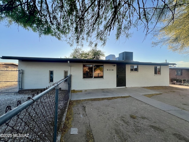 rear view of property featuring central AC, brick siding, fence, and a patio area
