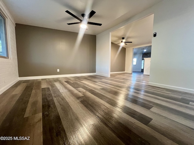 spare room with baseboards, wood finished floors, ceiling fan, and plenty of natural light