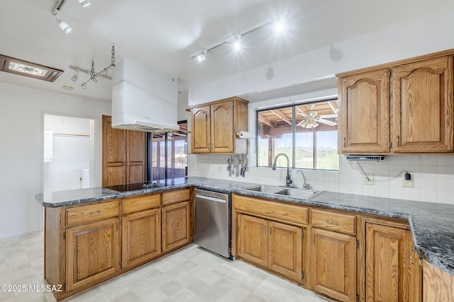 kitchen with a sink, brown cabinets, track lighting, a peninsula, and stainless steel dishwasher