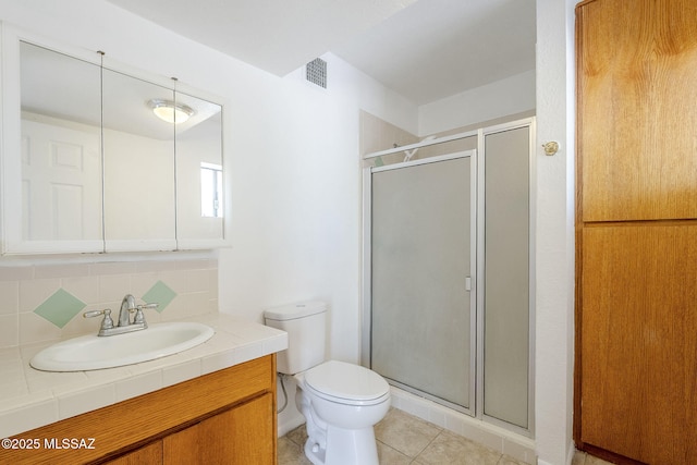 bathroom with a shower stall, vanity, tasteful backsplash, toilet, and tile patterned flooring