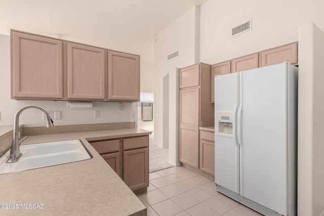kitchen featuring white fridge with ice dispenser, light countertops, visible vents, and a sink