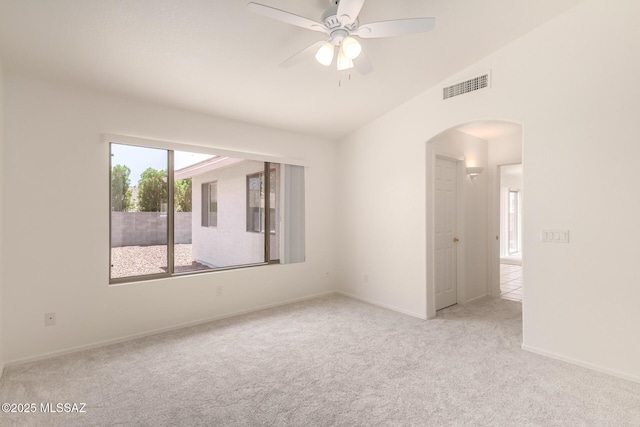 carpeted empty room with arched walkways, ceiling fan, baseboards, visible vents, and lofted ceiling