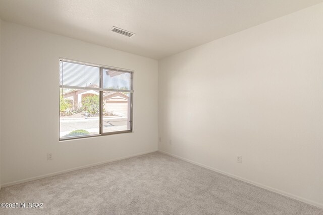 empty room with baseboards, visible vents, and carpet flooring