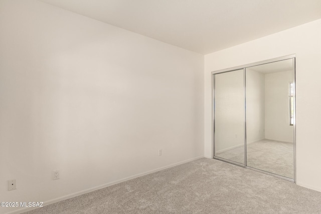 unfurnished bedroom with carpet, baseboards, and a closet