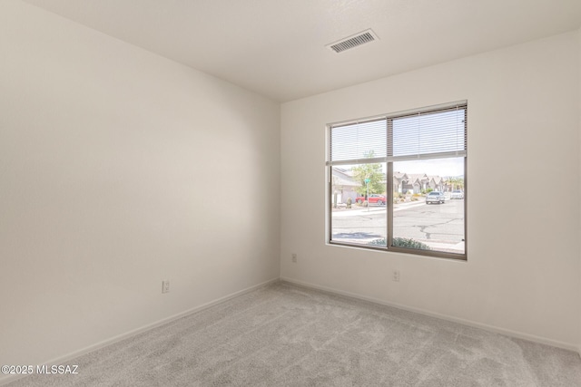 unfurnished room with visible vents, light colored carpet, and baseboards