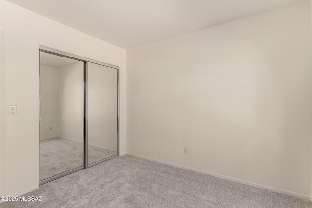 unfurnished bedroom featuring baseboards, carpet floors, and a closet
