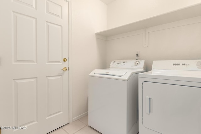 clothes washing area with light tile patterned floors, laundry area, and washer and clothes dryer
