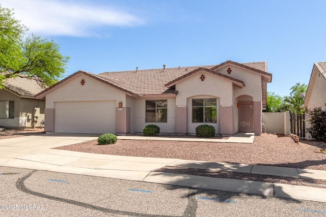 mediterranean / spanish-style home with a garage, concrete driveway, stucco siding, and a tiled roof