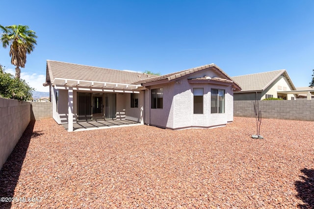 rear view of house with stucco siding, a tiled roof, a pergola, and a fenced backyard