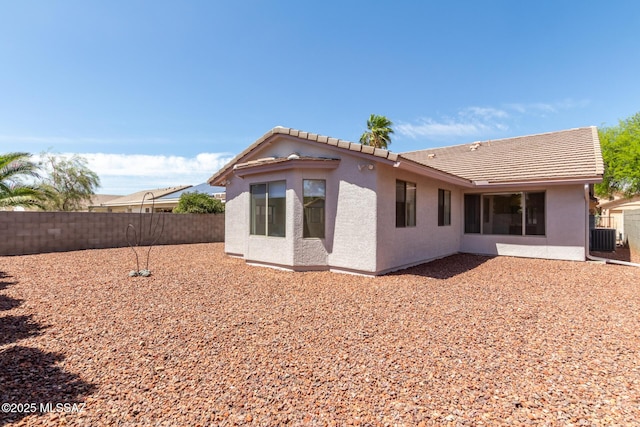 rear view of house with stucco siding, a tiled roof, and a fenced backyard