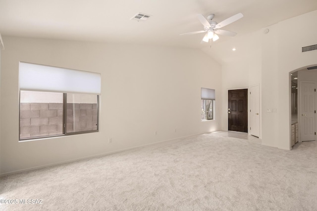 spare room featuring ceiling fan, high vaulted ceiling, visible vents, light carpet, and arched walkways
