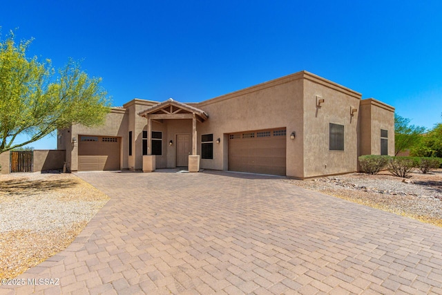 southwest-style home featuring decorative driveway, an attached garage, and stucco siding