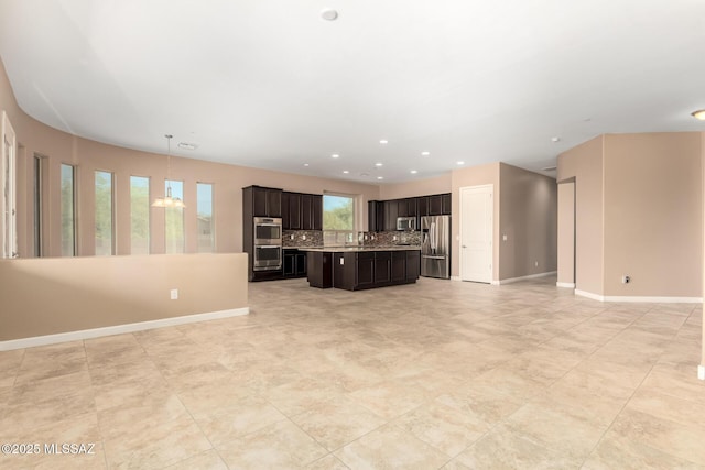 kitchen with open floor plan, a center island, light countertops, backsplash, and stainless steel appliances