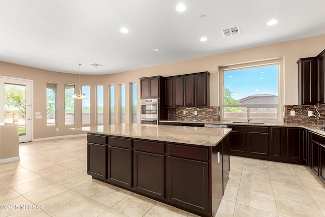 kitchen with decorative backsplash, light tile patterned flooring, a kitchen island, stainless steel double oven, and a sink