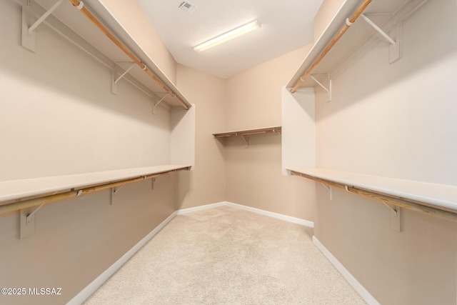 walk in closet featuring visible vents and light carpet
