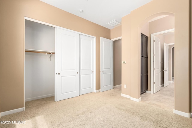 unfurnished bedroom with arched walkways, baseboards, and light carpet