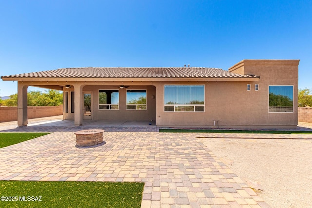 back of property with ceiling fan, fence, a patio, a tiled roof, and an outdoor fire pit