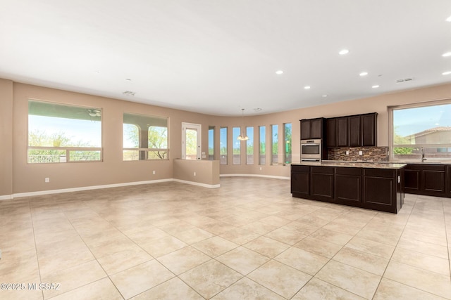 kitchen with baseboards, light countertops, light tile patterned floors, a sink, and backsplash