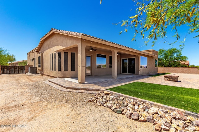 back of property featuring an outdoor fire pit, ceiling fan, stucco siding, a fenced backyard, and a patio area