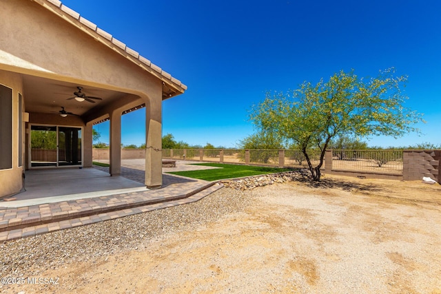 view of yard featuring a fenced backyard, a ceiling fan, and a patio area