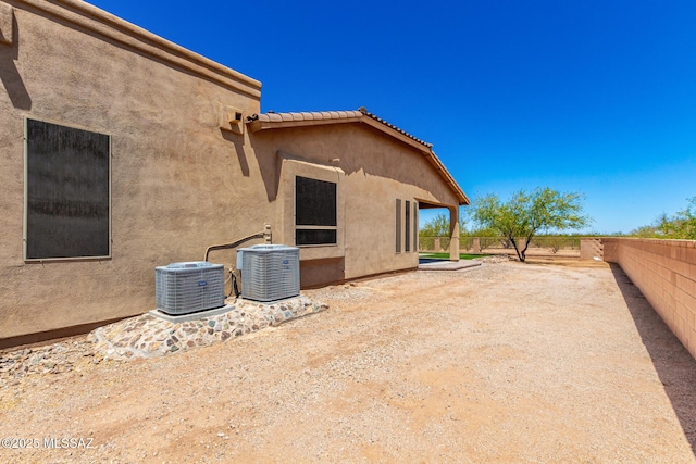 back of house with stucco siding, a fenced backyard, and central air condition unit