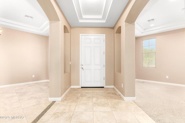 foyer entrance with a raised ceiling, arched walkways, and visible vents