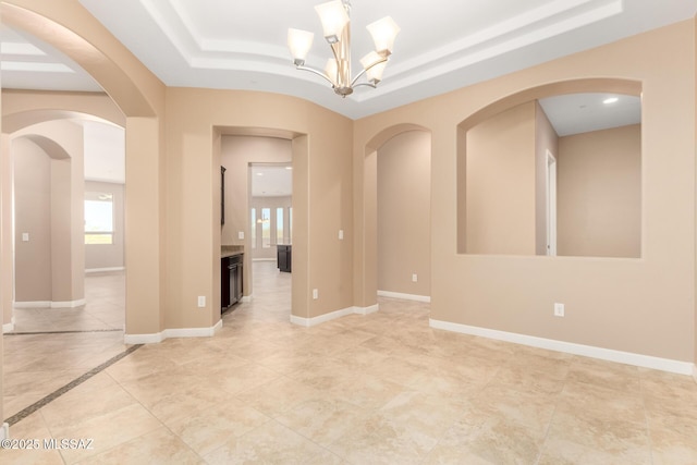 unfurnished room featuring an inviting chandelier, baseboards, recessed lighting, a raised ceiling, and arched walkways