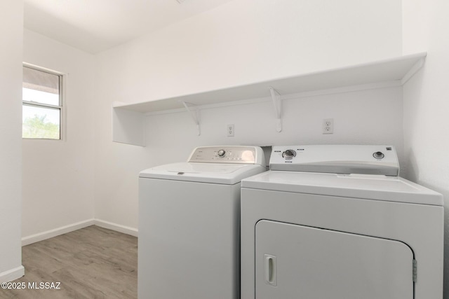 washroom featuring baseboards, light wood-style floors, laundry area, and independent washer and dryer