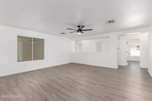 empty room with baseboards, visible vents, wood finished floors, and a ceiling fan