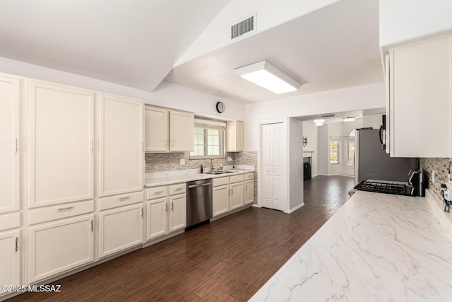 kitchen with a sink, appliances with stainless steel finishes, tasteful backsplash, and visible vents