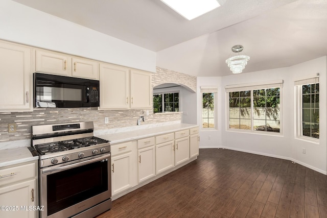 kitchen with black microwave, gas stove, light countertops, decorative backsplash, and lofted ceiling