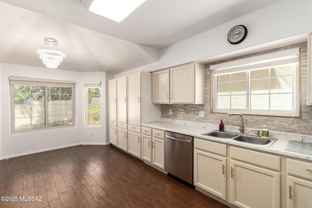 kitchen with stainless steel dishwasher, backsplash, a sink, and light countertops