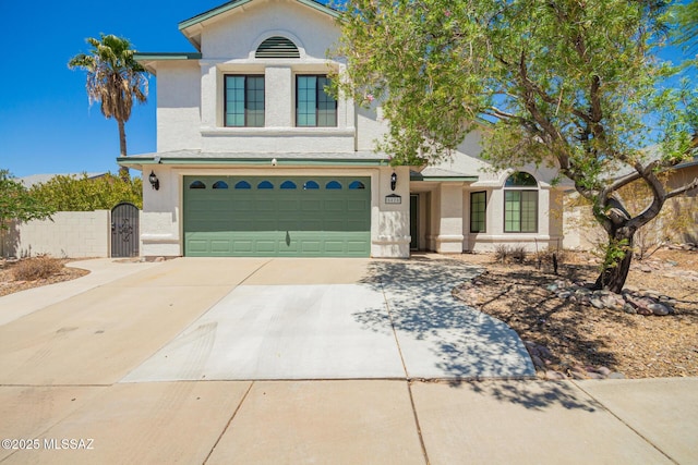 view of front of house featuring a gate, an attached garage, stucco siding, and concrete driveway