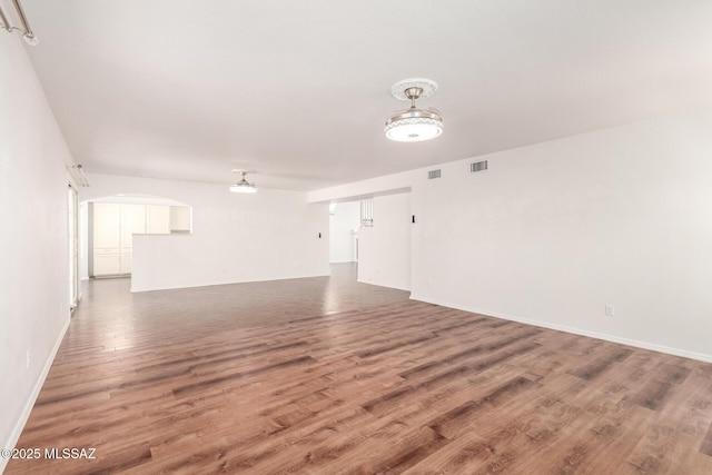unfurnished living room featuring baseboards, wood finished floors, and visible vents