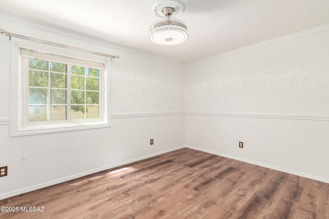 spare room featuring baseboards, ornamental molding, and wood finished floors