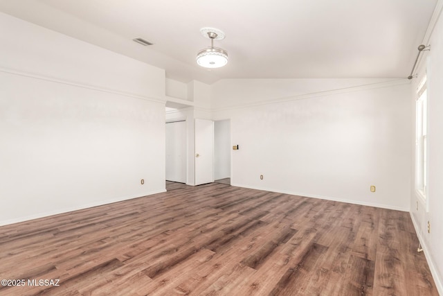 spare room with baseboards, visible vents, wood finished floors, and lofted ceiling