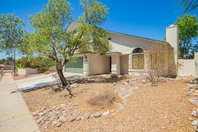 view of front of house with a garage, fence, stucco siding, a chimney, and concrete driveway
