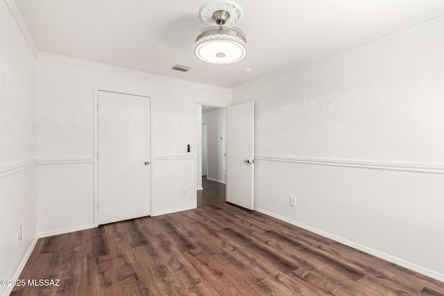 unfurnished bedroom with baseboards, visible vents, ornamental molding, and wood finished floors