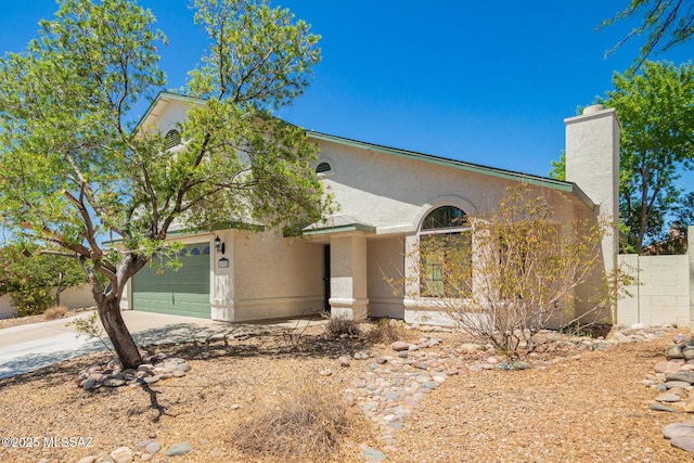 view of front facade with fence, stucco siding, concrete driveway, and a chimney