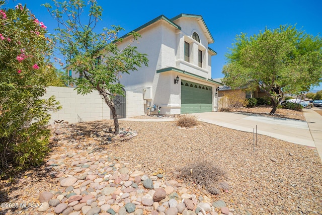 view of front of home with a garage, stucco siding, driveway, and fence