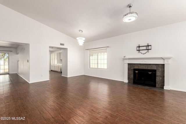 unfurnished living room with visible vents, dark wood finished floors, a tiled fireplace, and vaulted ceiling