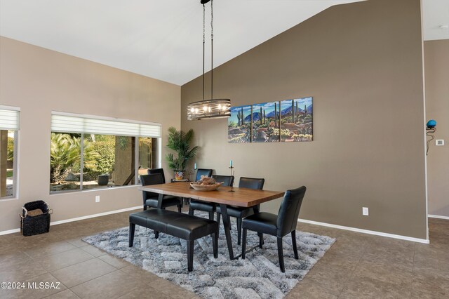 tiled dining space featuring high vaulted ceiling, baseboards, and a notable chandelier
