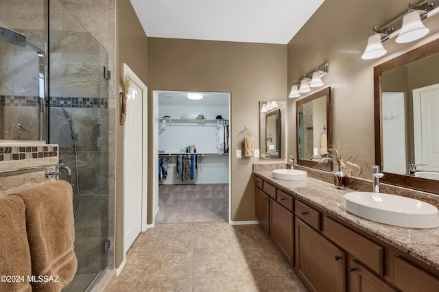 bathroom with a shower stall, a sink, a spacious closet, and double vanity