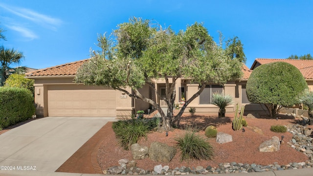 view of front of home with an attached garage, a tile roof, concrete driveway, and stucco siding